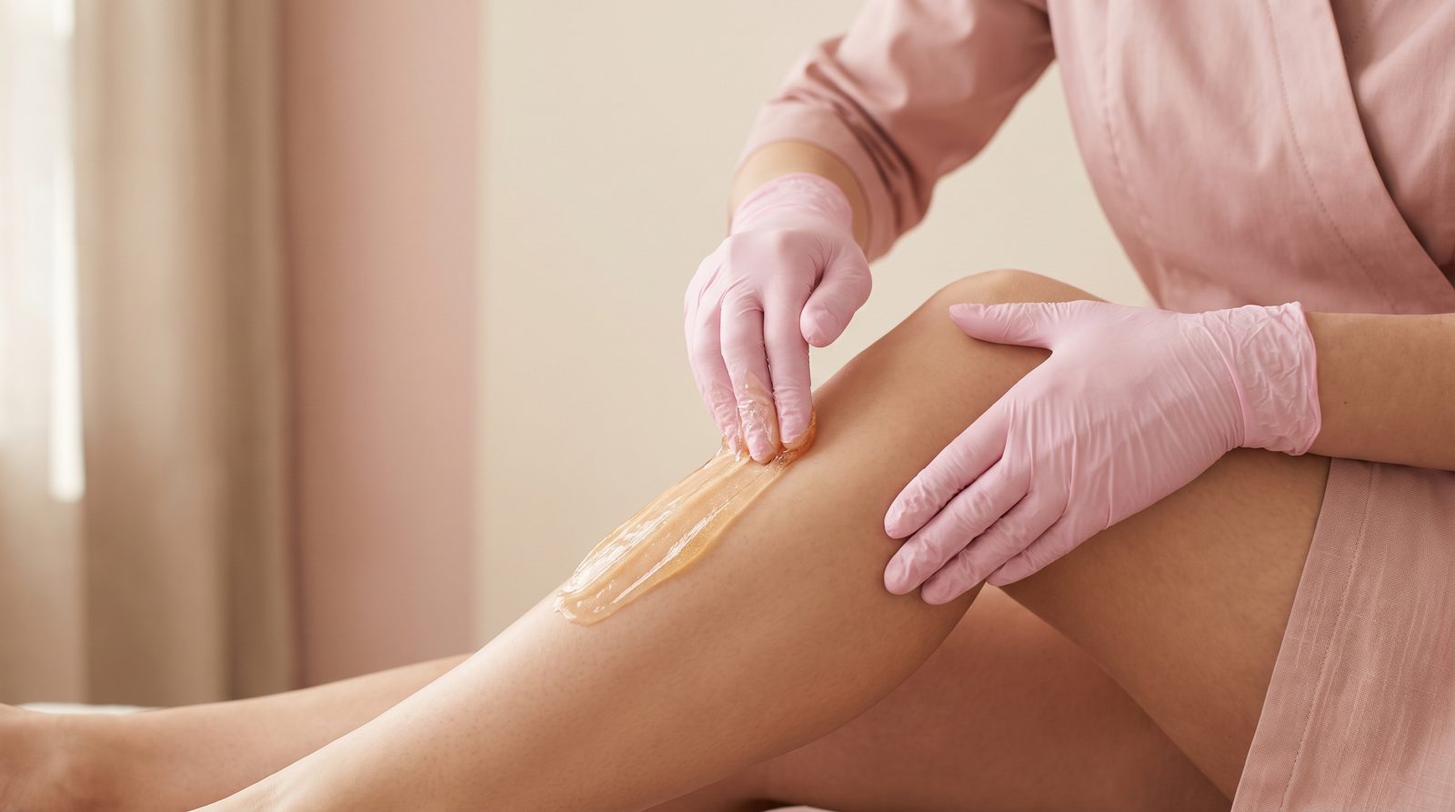 Esthetician applying sugar paste to a client’s leg